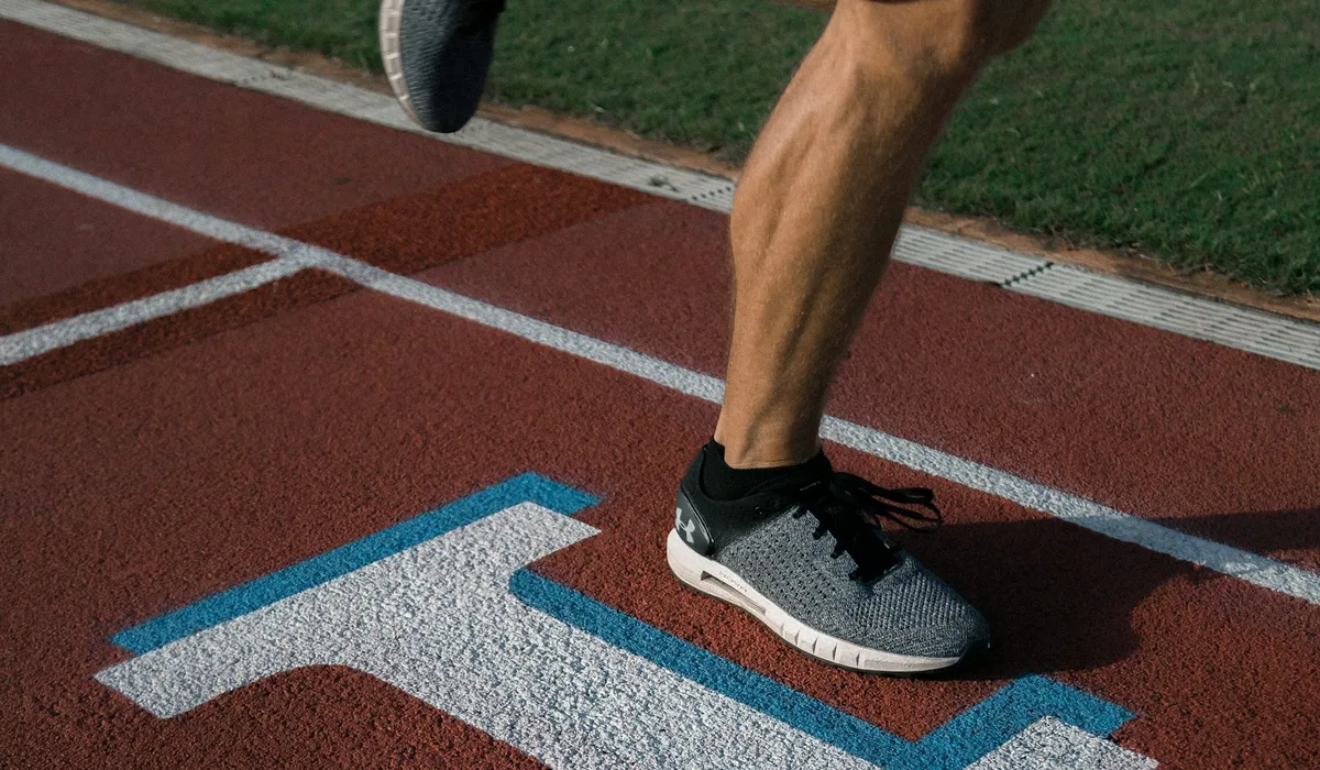 Coureur seul sur piste en séance de fractionnés — effort maximal, posture de sprint
